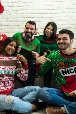 group of friends having fun with a holiday sweater party 